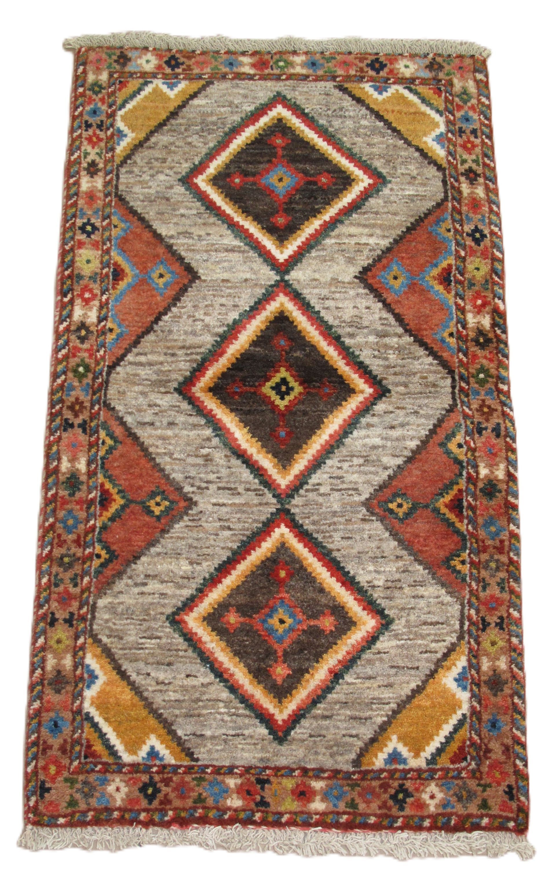 Colorful geometric woven rug with diamond patterns in red, orange, black, and cream