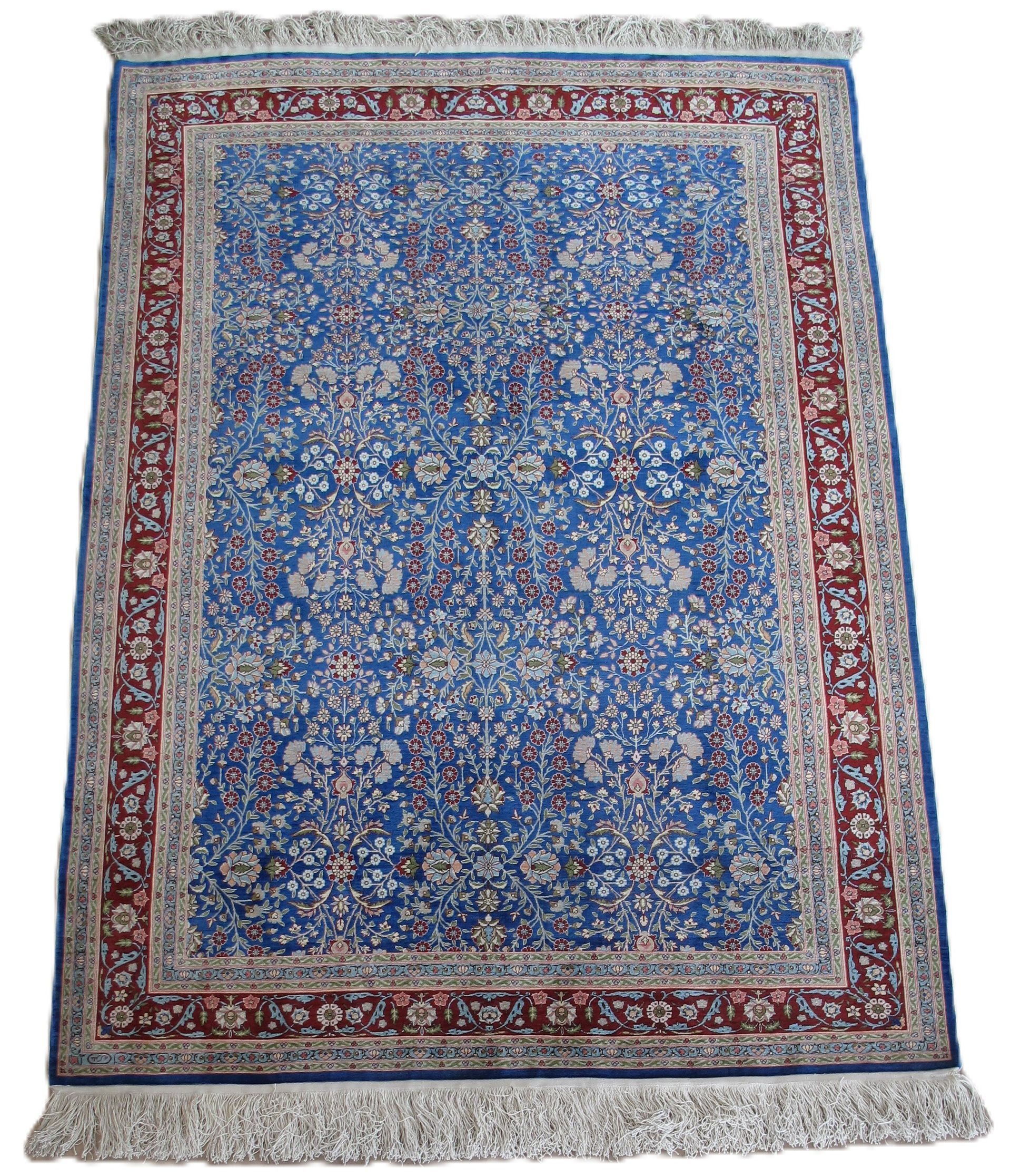 Blue rectangular rug with red and white border and fringe.