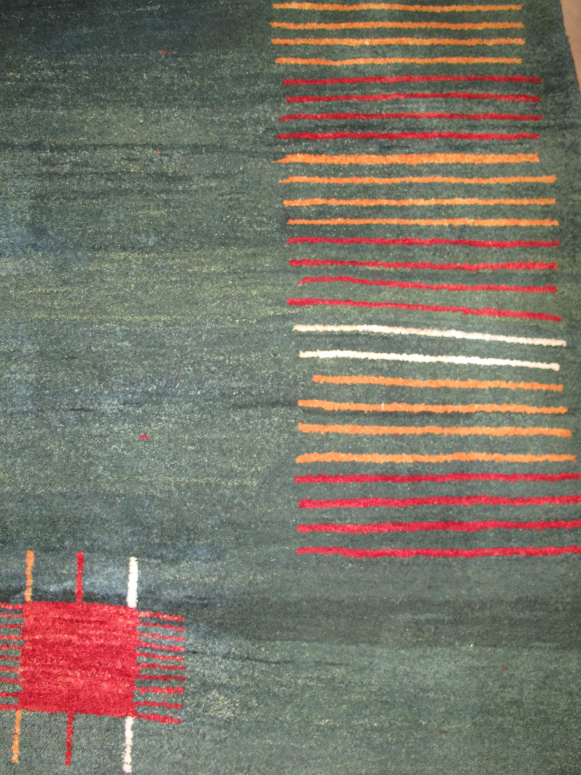 Blue area rug with red, white, and brown geometric designs.