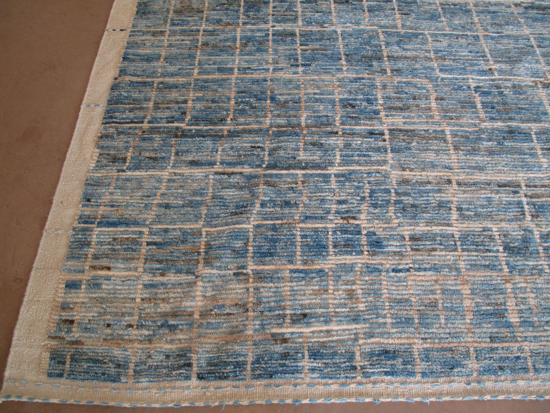 Blue and beige patterned area rug on a white background