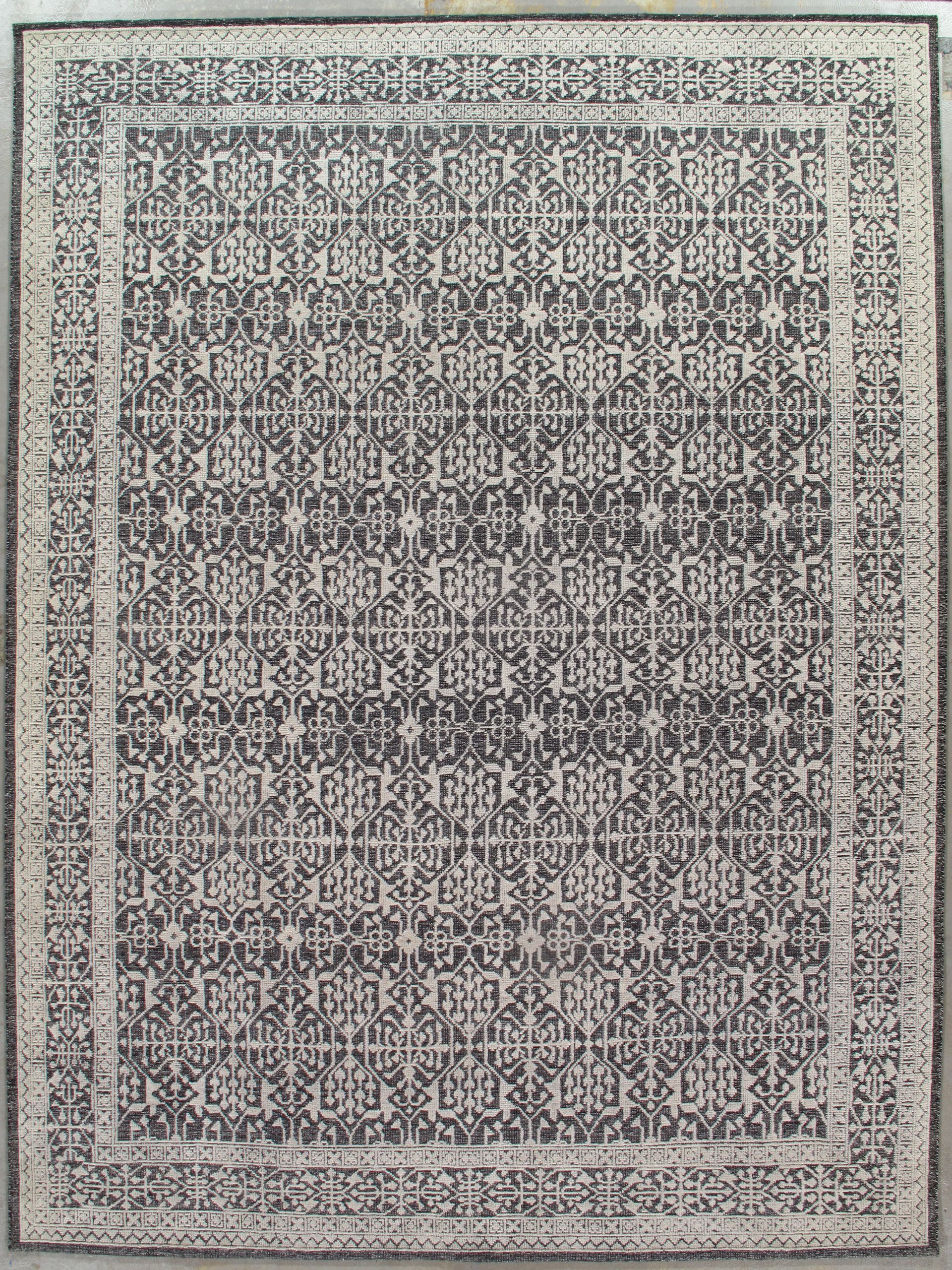 Dense black-and-white patterned textile with a decorative border