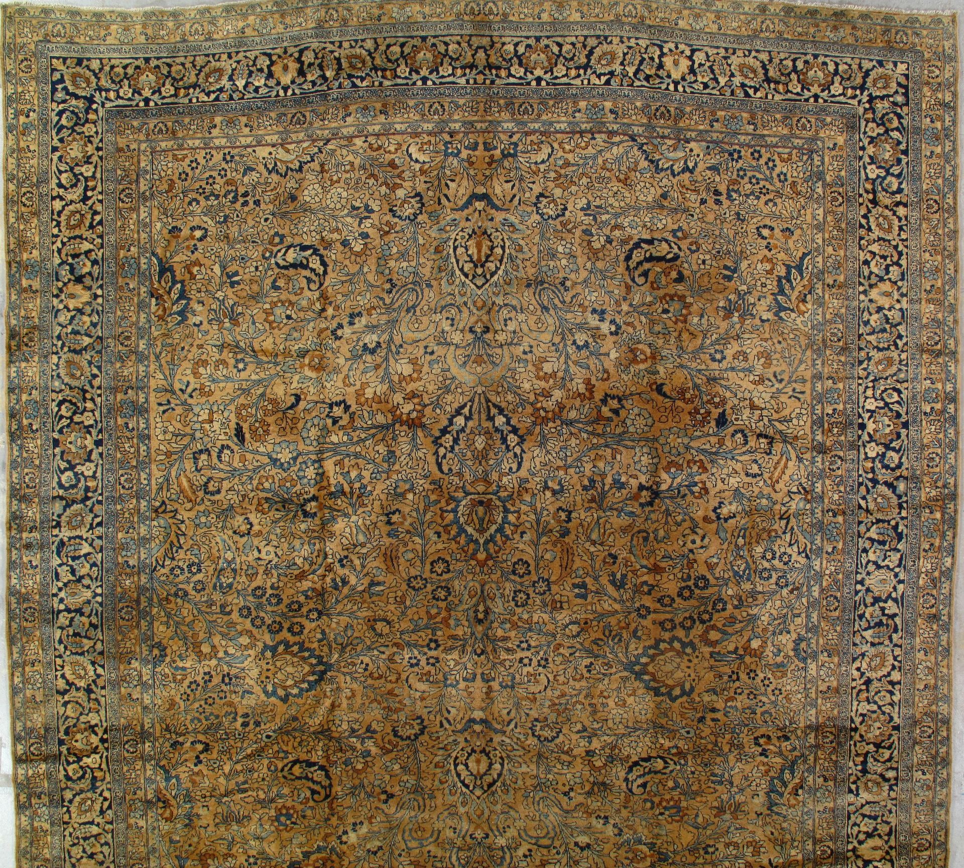 A faded ornate beige and blue patterned rug with a decorative border