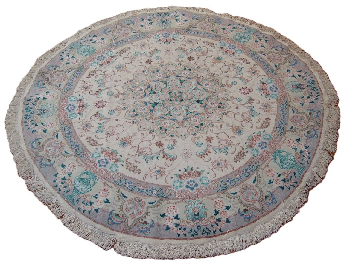 Round Persian rug, off-white with floral patterns, blue and pink accents, fringed edge.