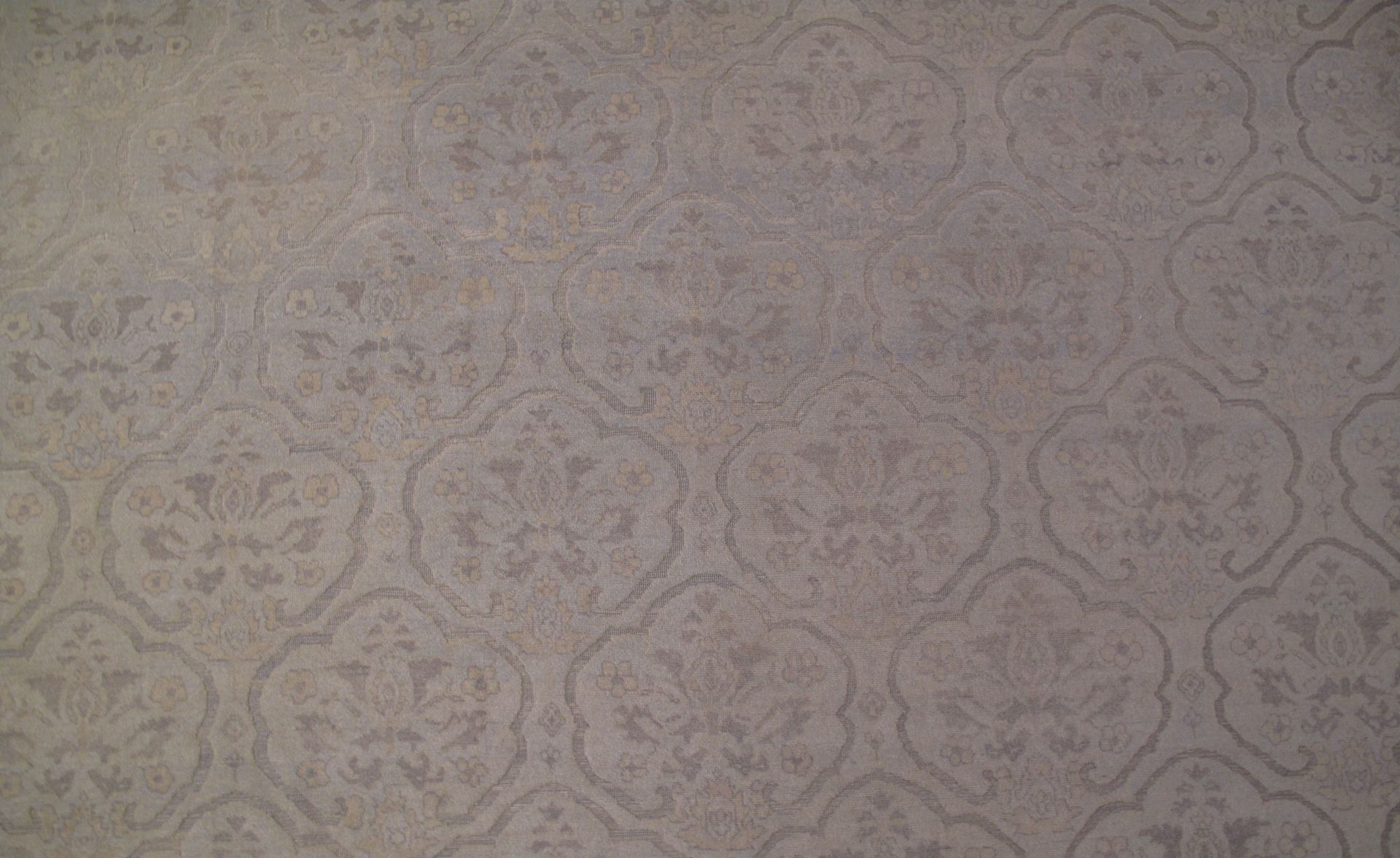 Gray patterned carpet filling the frame with a subtle floral design