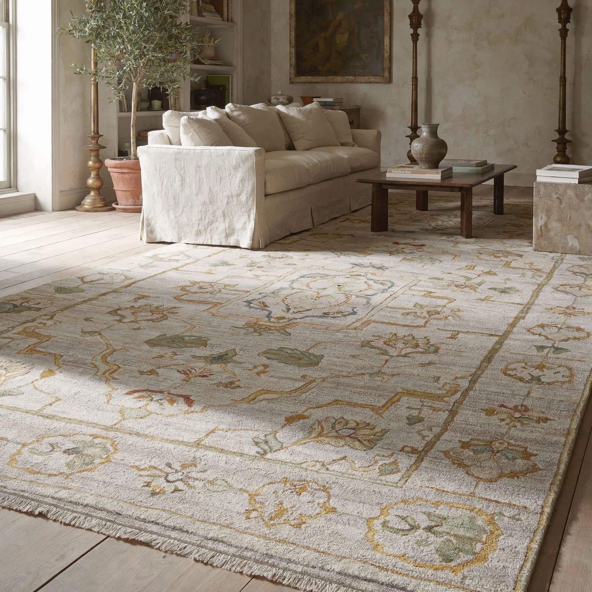 Beige living room with a large patterned Oushak rug, cream sofa, and rustic coffee table.