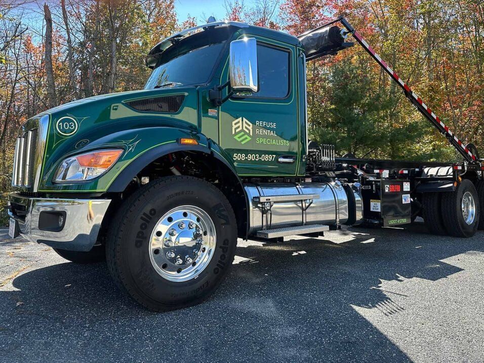 A green dump truck is parked on the side of the road.