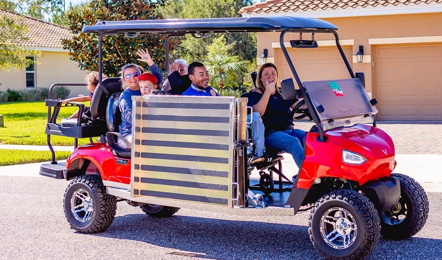 A group of people are riding in a red golf cart.