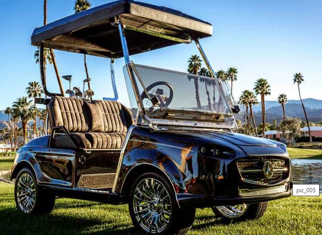 A black golf cart is parked on a lush green field.