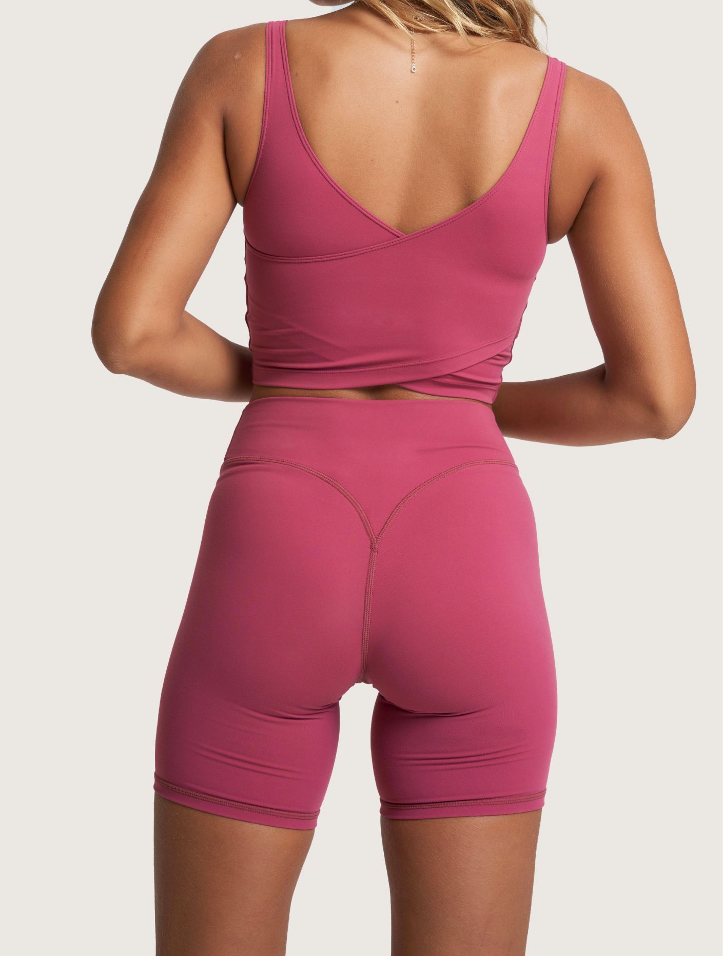 Woman wearing a blue cropped tank top and matching leggings against a plain background