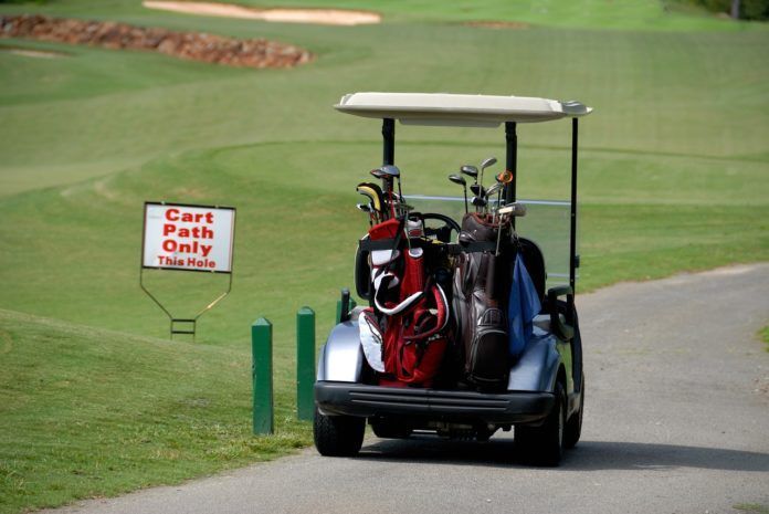 A golf cart is driving down a path with a sign that says cart path only
