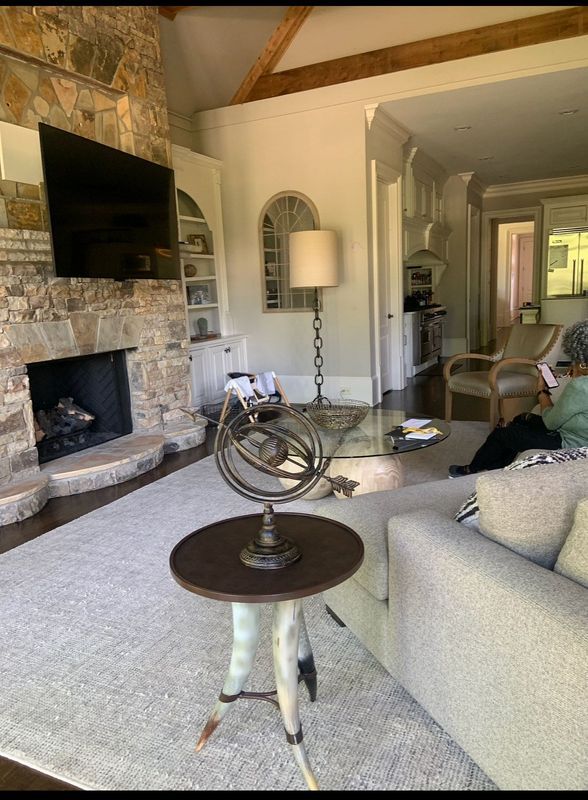 Cozy living room with stone fireplace, wall-mounted TV, and beige sofa under exposed wood beams