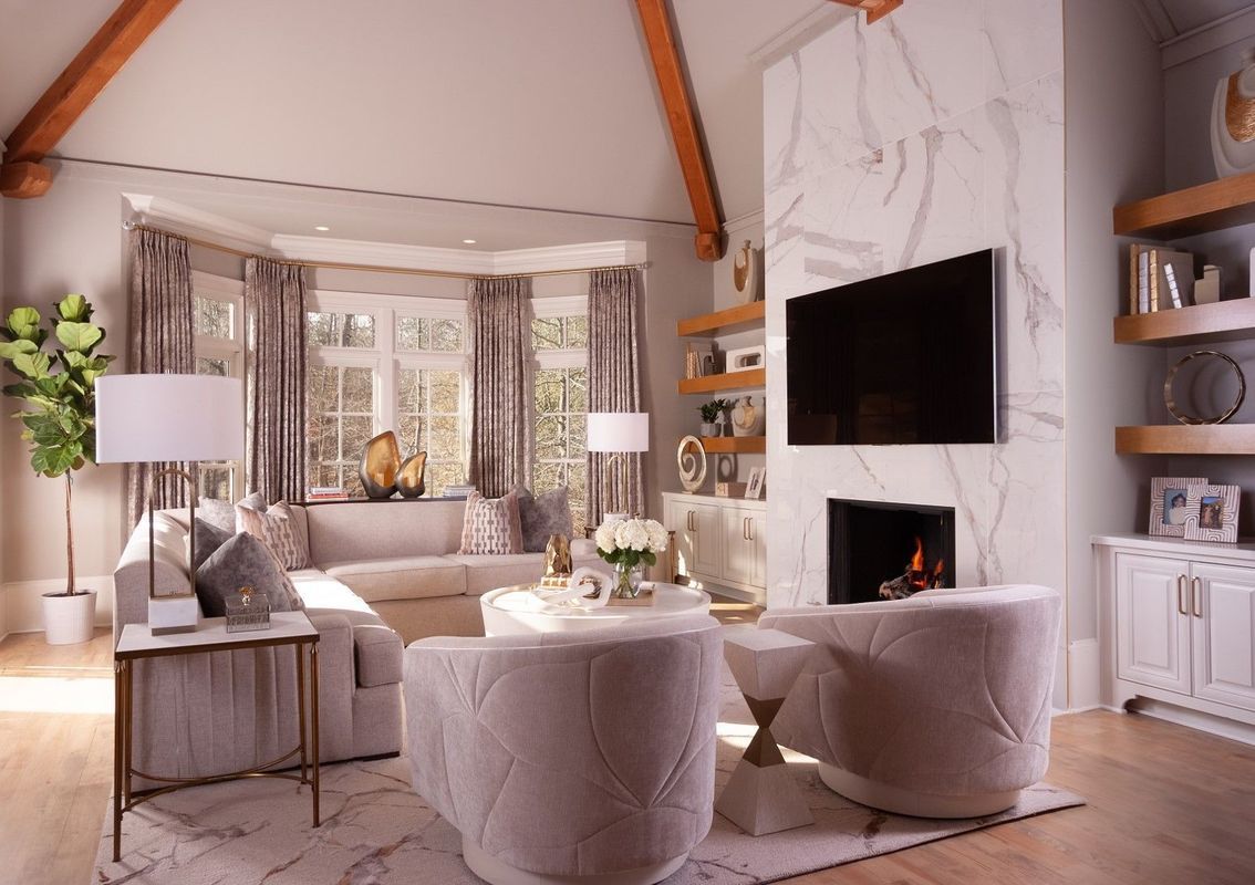 Bright modern living room with sofa, armchairs, fireplace, TV, and large windows