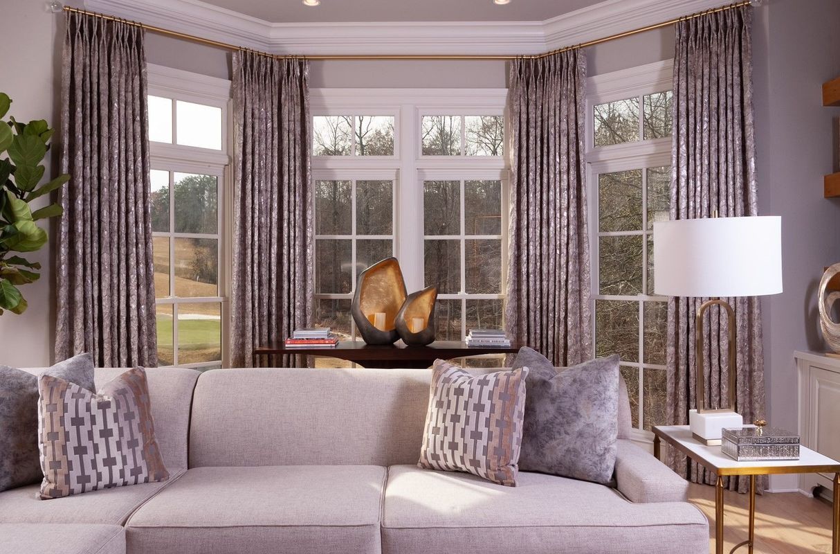 Elegant living room with bay windows, gray sofa, patterned curtains, and a floor lamp.