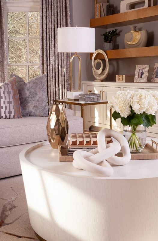 Modern living room with a white coffee table, lamp, gold decor, and a vase of white flowers