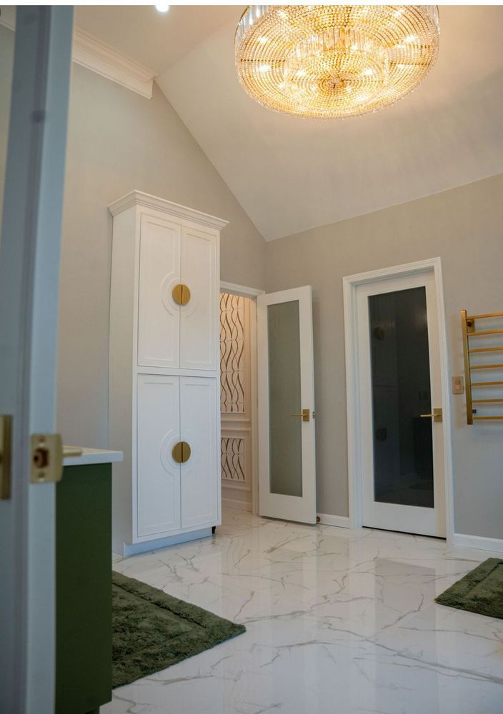 Bright entry foyer with white marble floor, tall cabinets, gold ceiling light, and open doorways