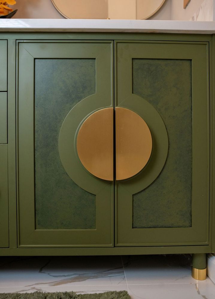 Green cabinet with two doors and a round gold center detail