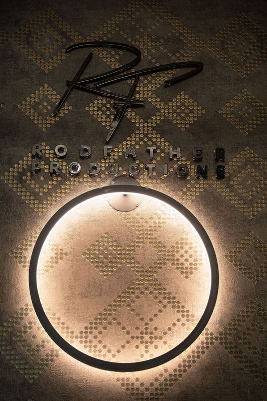 Close-up of a backlit circular wall mirror or light with stylized text above it on a patterned wall.