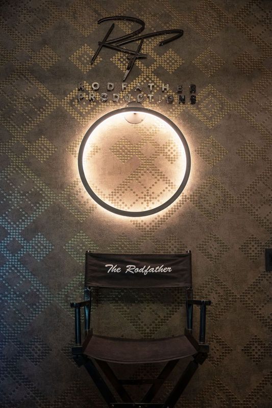 Illuminated wall sign above a director’s chair in a dim, patterned interior