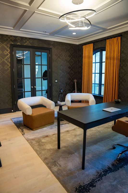 Modern living room with dark walls, blue curtains, a black coffee table, and white lounge chairs near glass doors