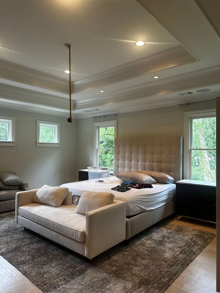 Modern bedroom with a king bed, tufted headboard, rugs, and large windows overlooking greenery