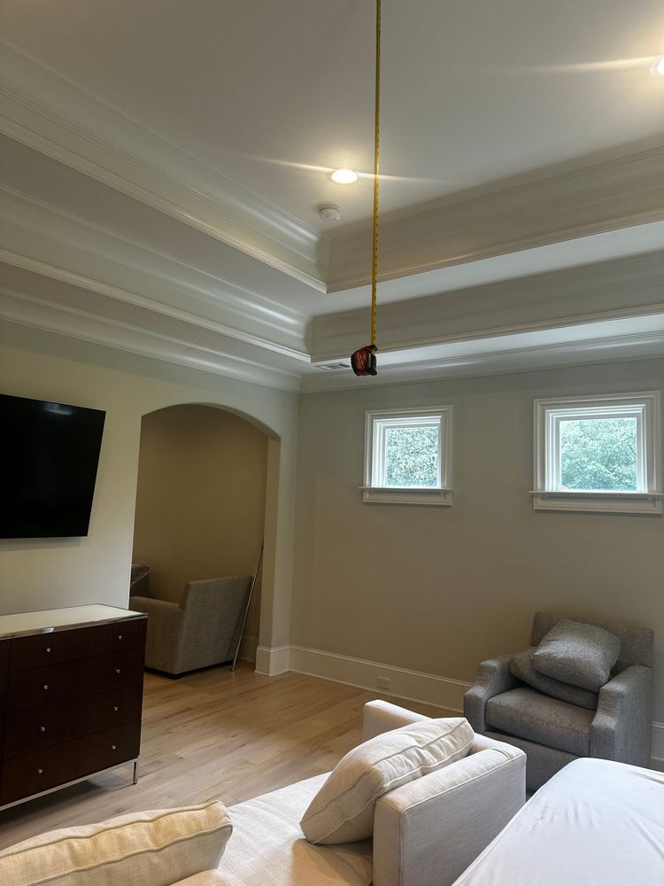 Living room with white coffered ceiling, wall-mounted TV, two windows, and gray chairs with a couch