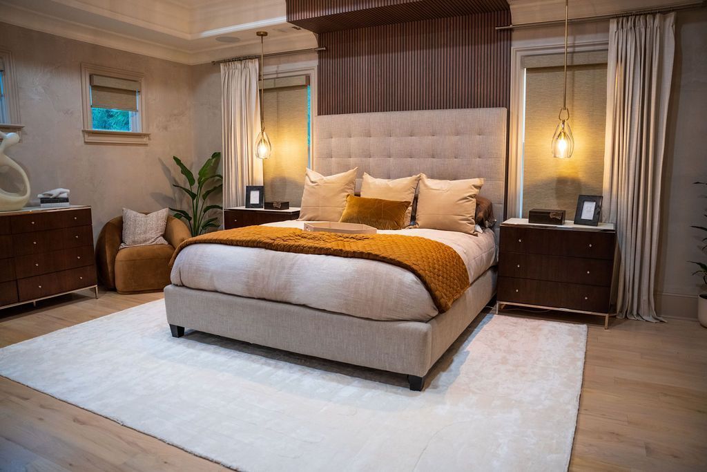 Stylish bedroom with a large bed, warm lighting, beige curtains, and a white rug