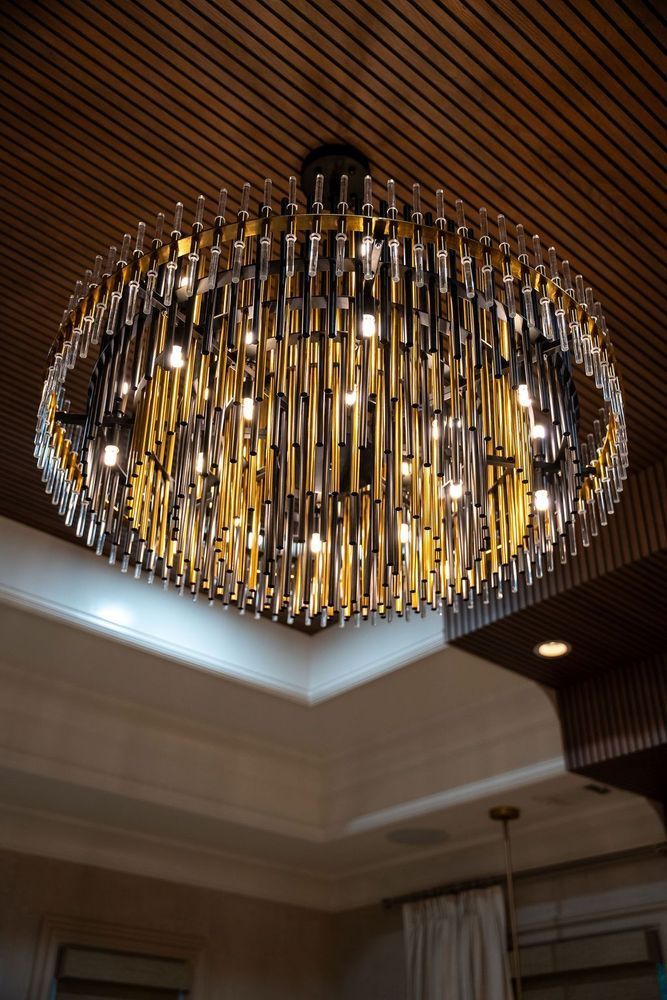 Large crystal chandelier with gold accents hanging from a coffered ceiling in a room