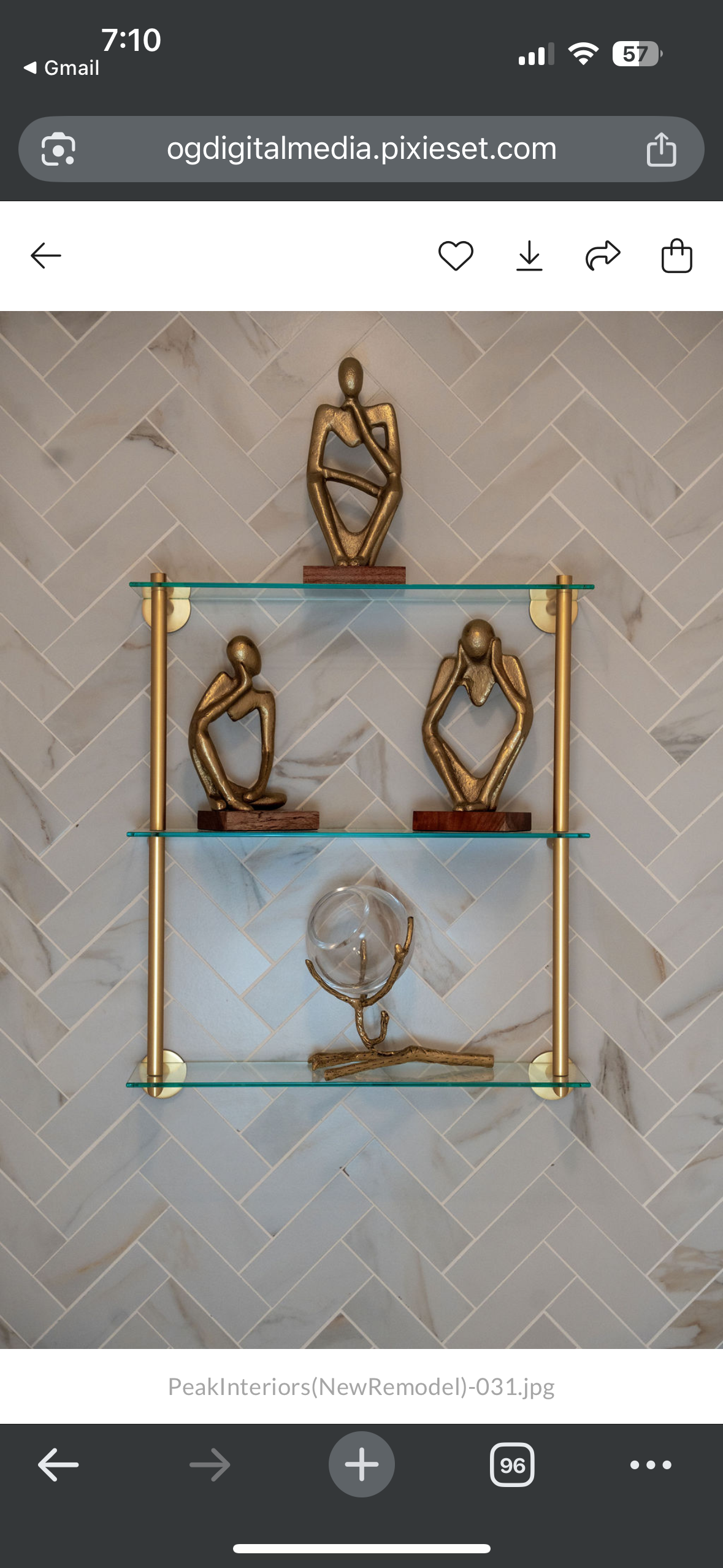 Gold decorative shelf with figurines and a clear glass sculpture on a patterned wall