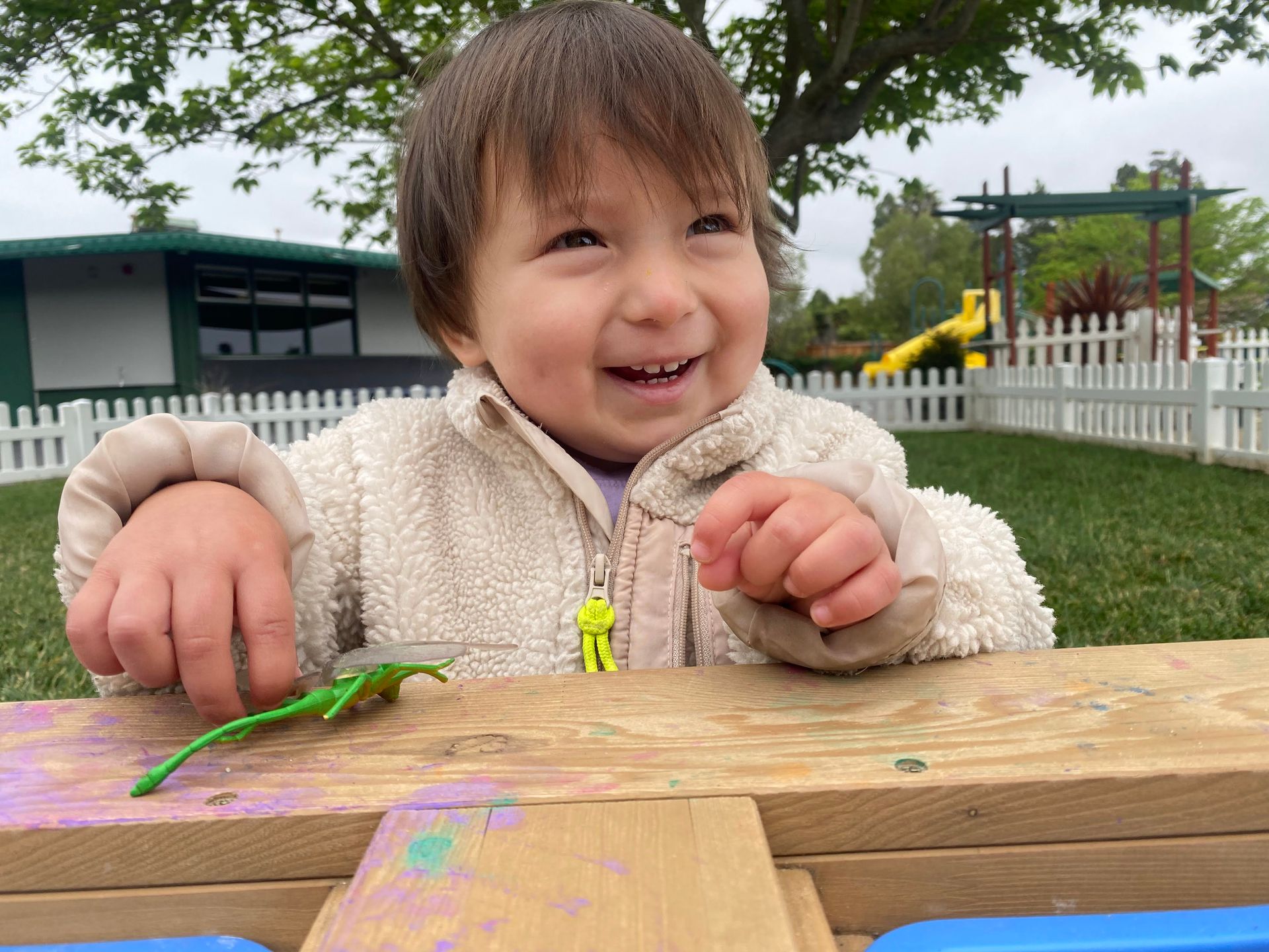 A Montessori child is sitting on a wooden table playing with a toy.