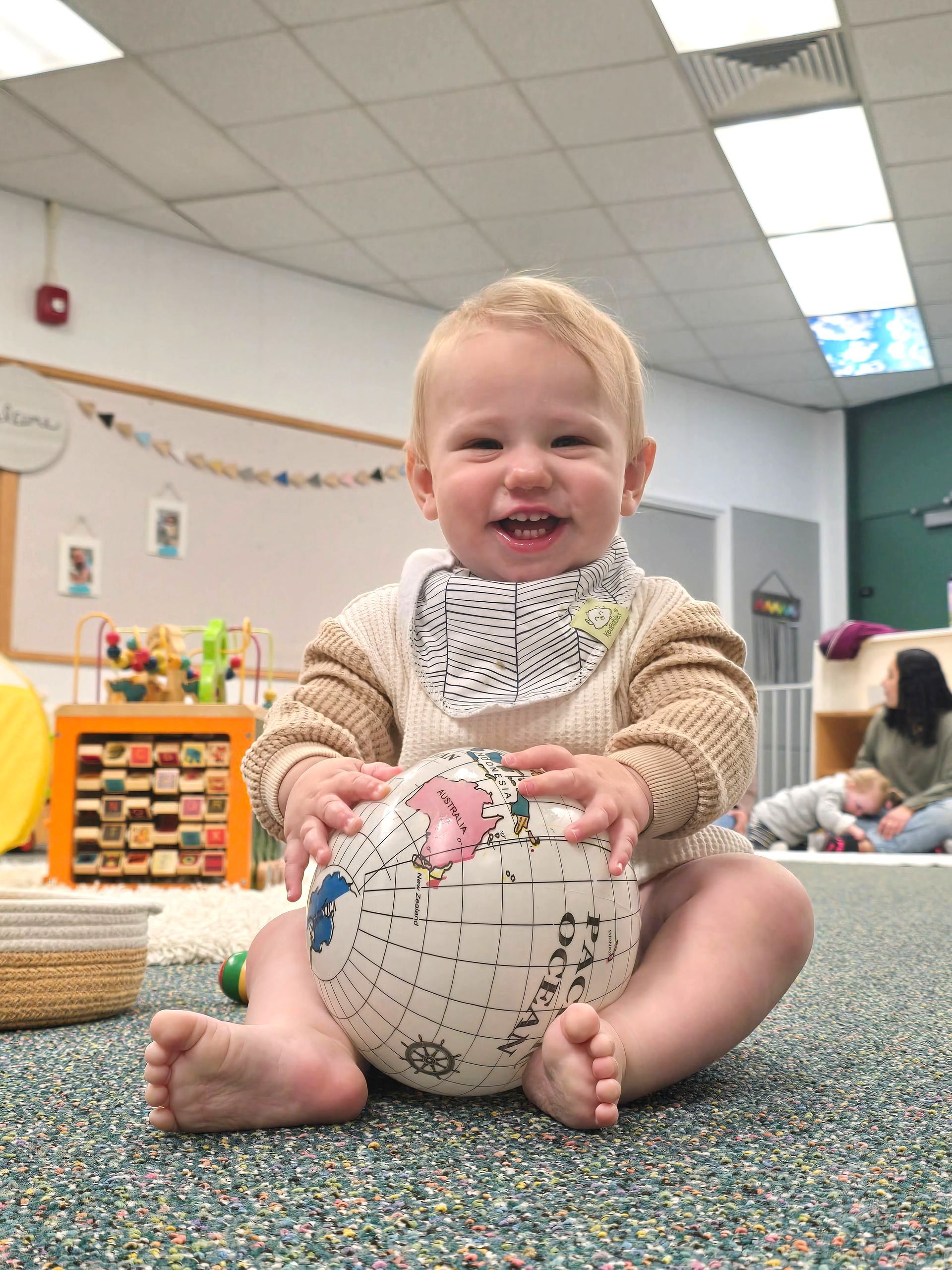 Montessori infant holding a plastic globe.