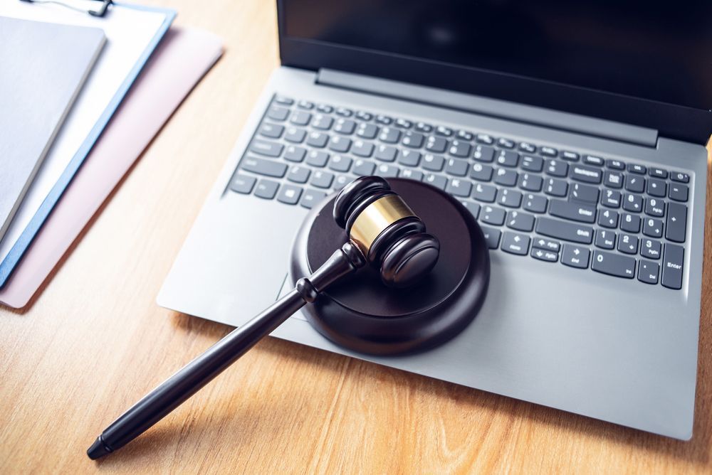 A judge 's gavel is sitting on top of a laptop computer.