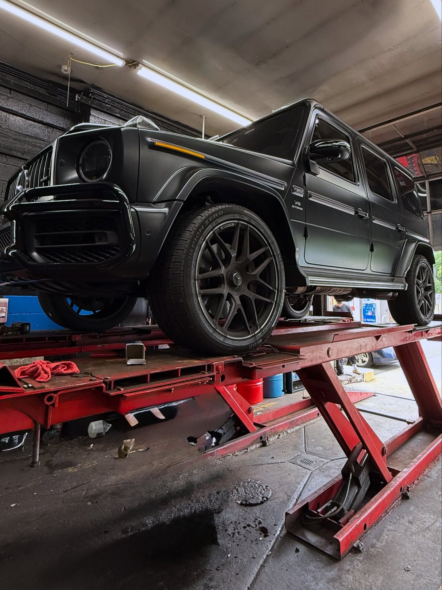 Black SUV on a red car lift inside an auto shop, viewed from a low angle. | Auto Obsessions Auto Repair