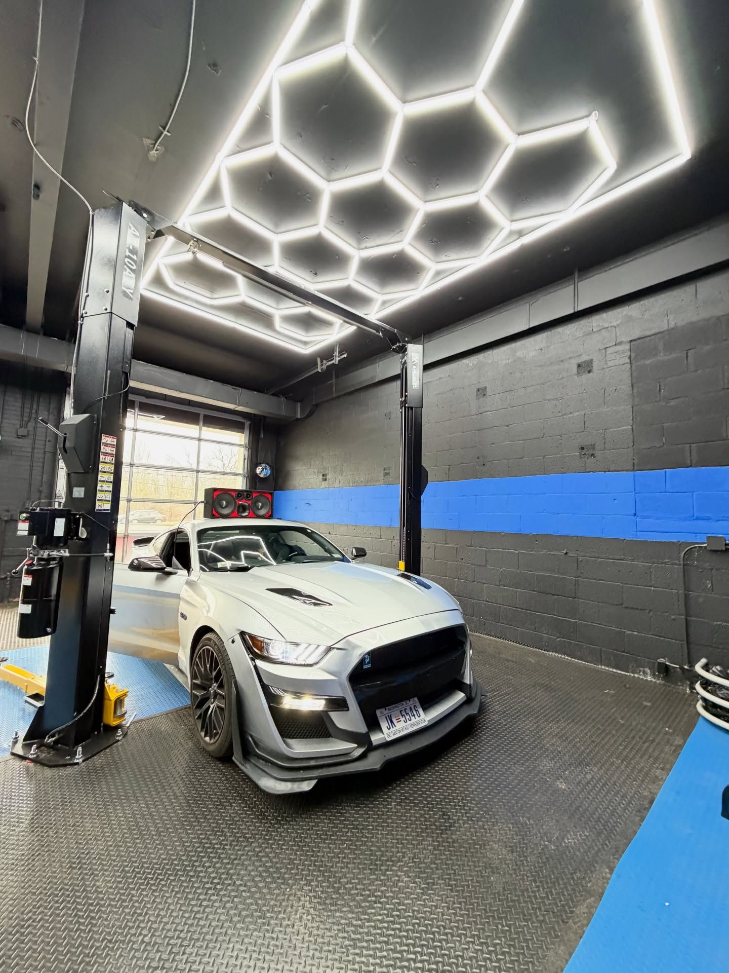 White sports car in a sleek indoor car wash bay with hexagonal ceiling lights | Auto Obsessions Auto Repair