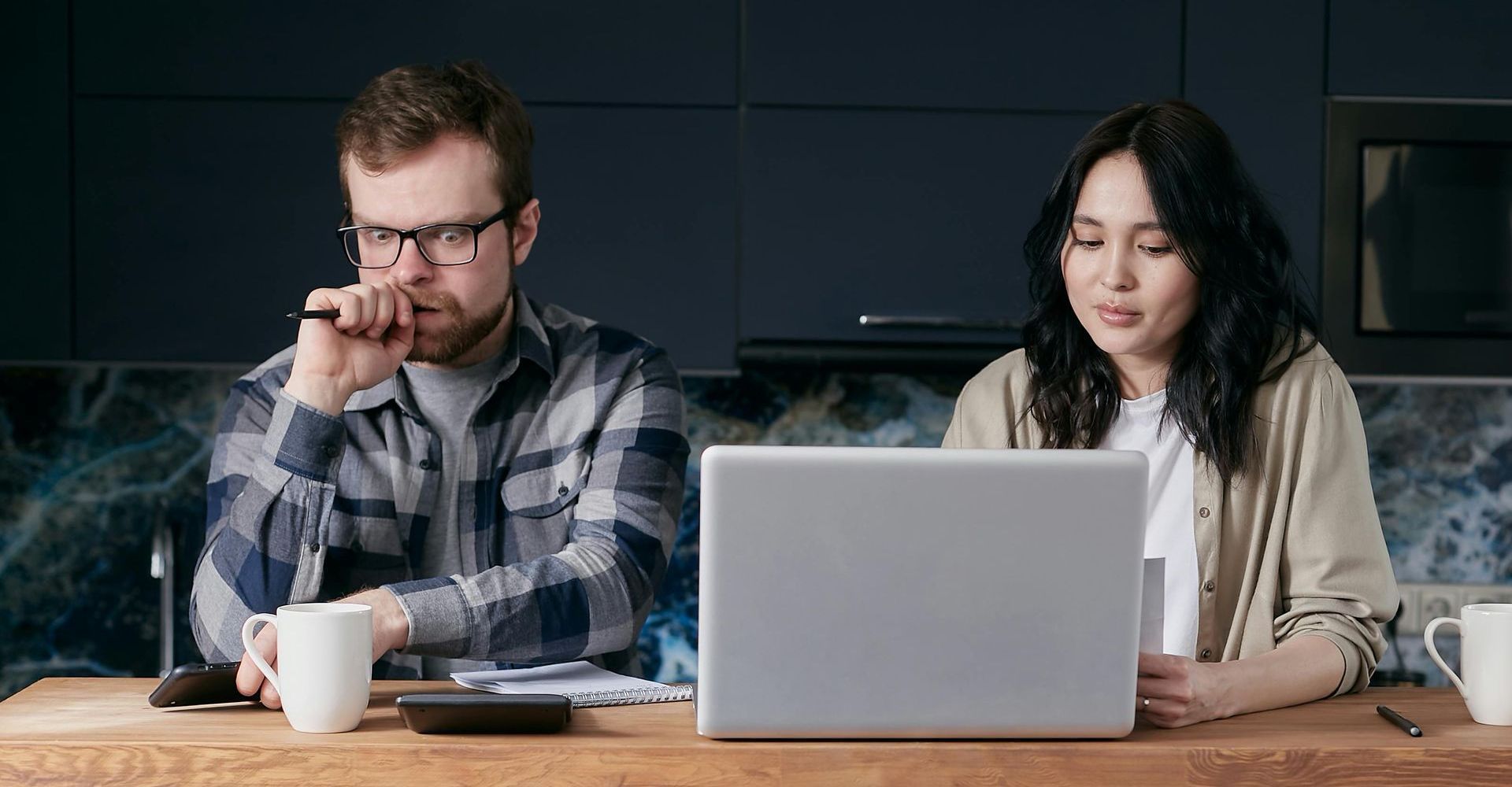 Two people working at a table with a laptop in a dimly lit office