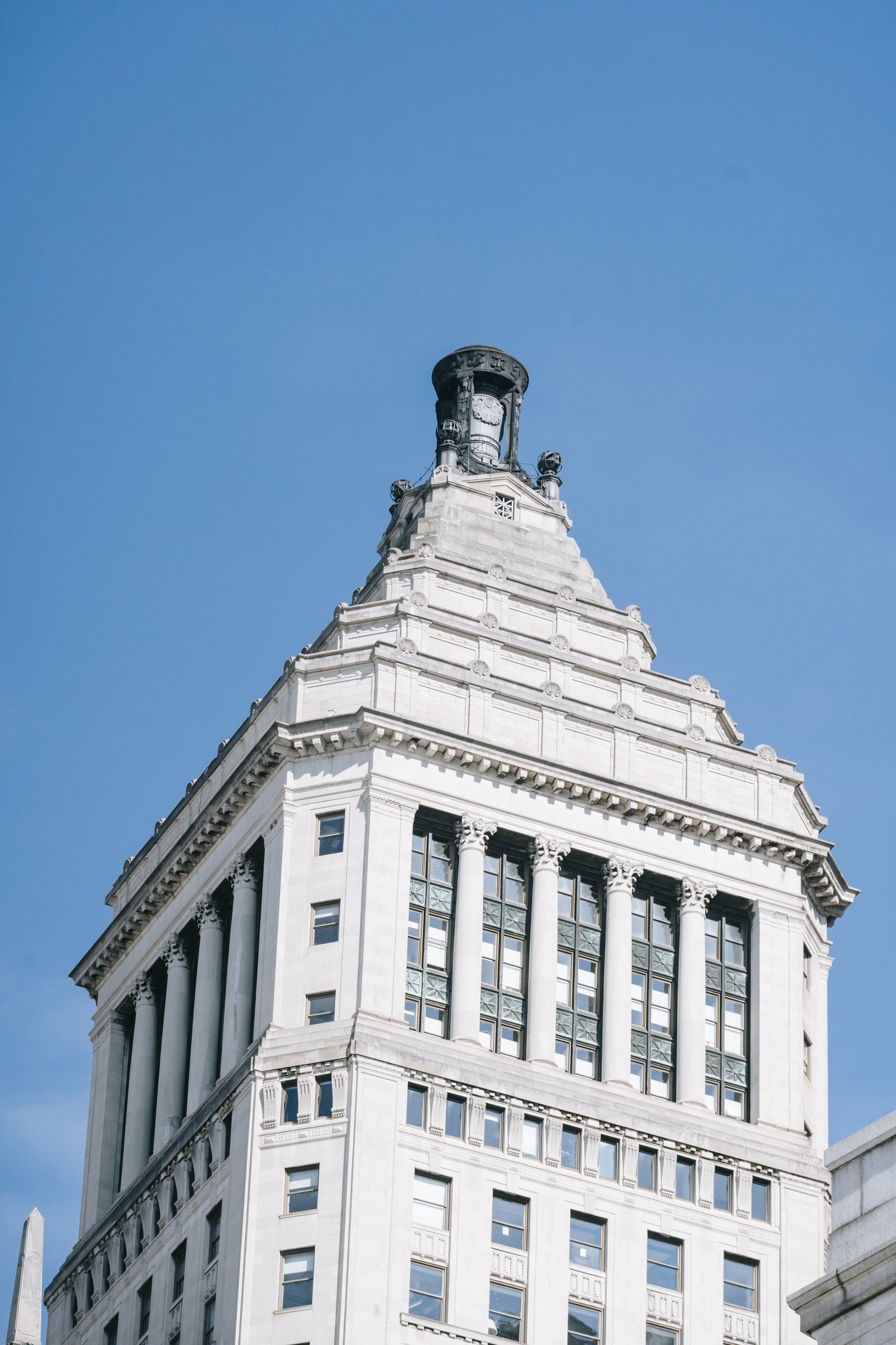 White historic skyscraper against a clear blue sky, viewed from below