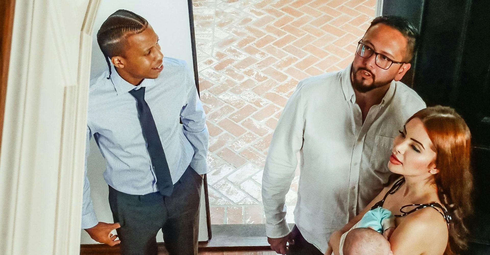 Three coworkers conversing in a doorway, one holding a tablet, viewed from above