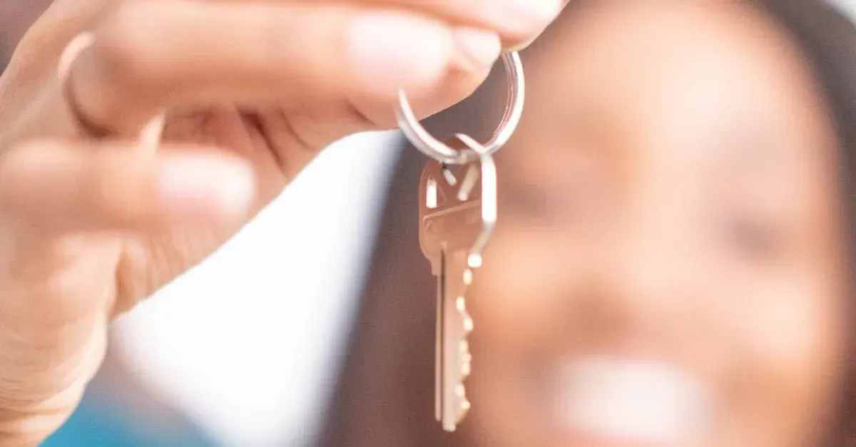 Hand holding two silver keys against a blurred background
