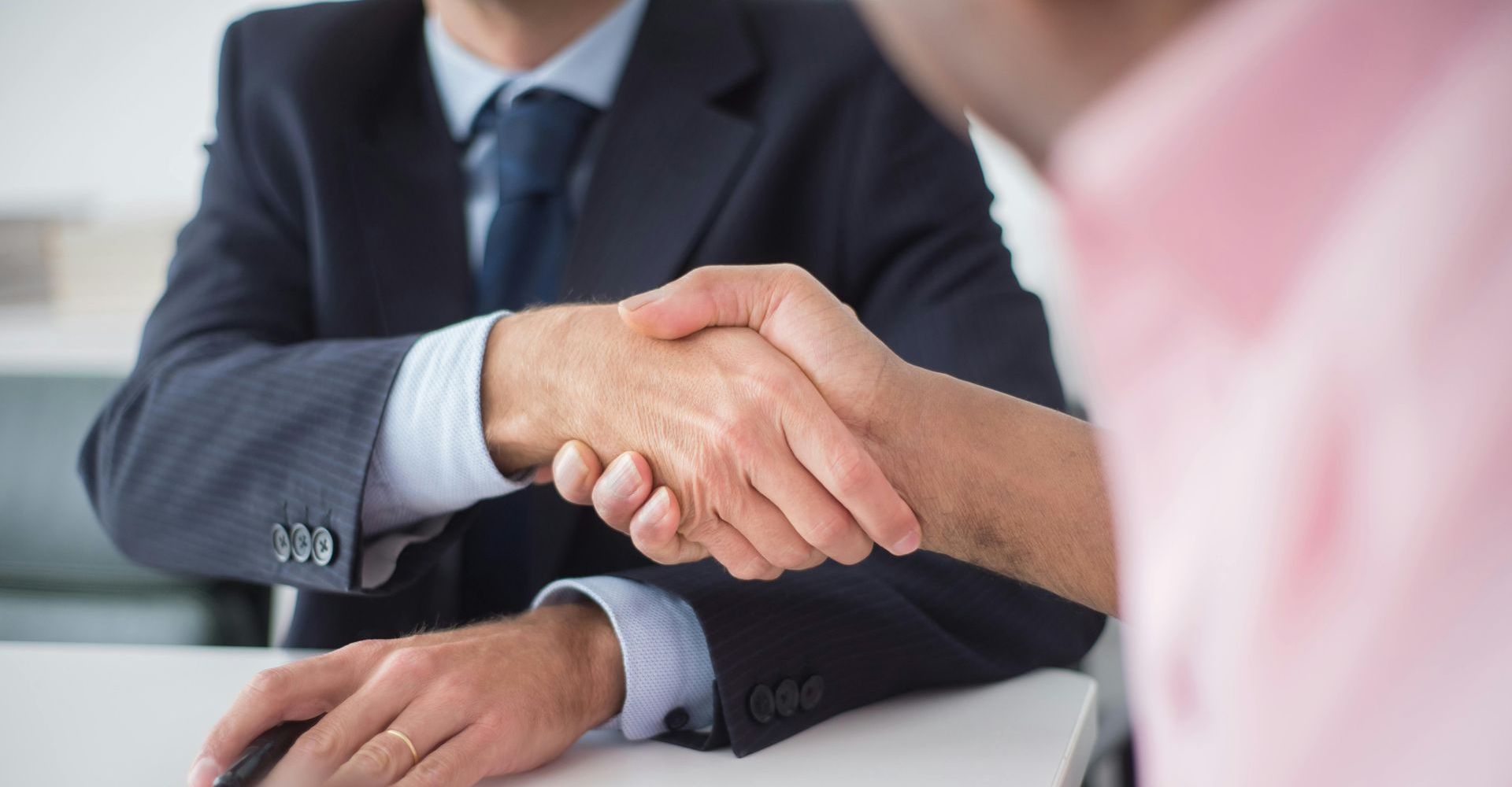Businesspeople shaking hands across a desk in a meeting room