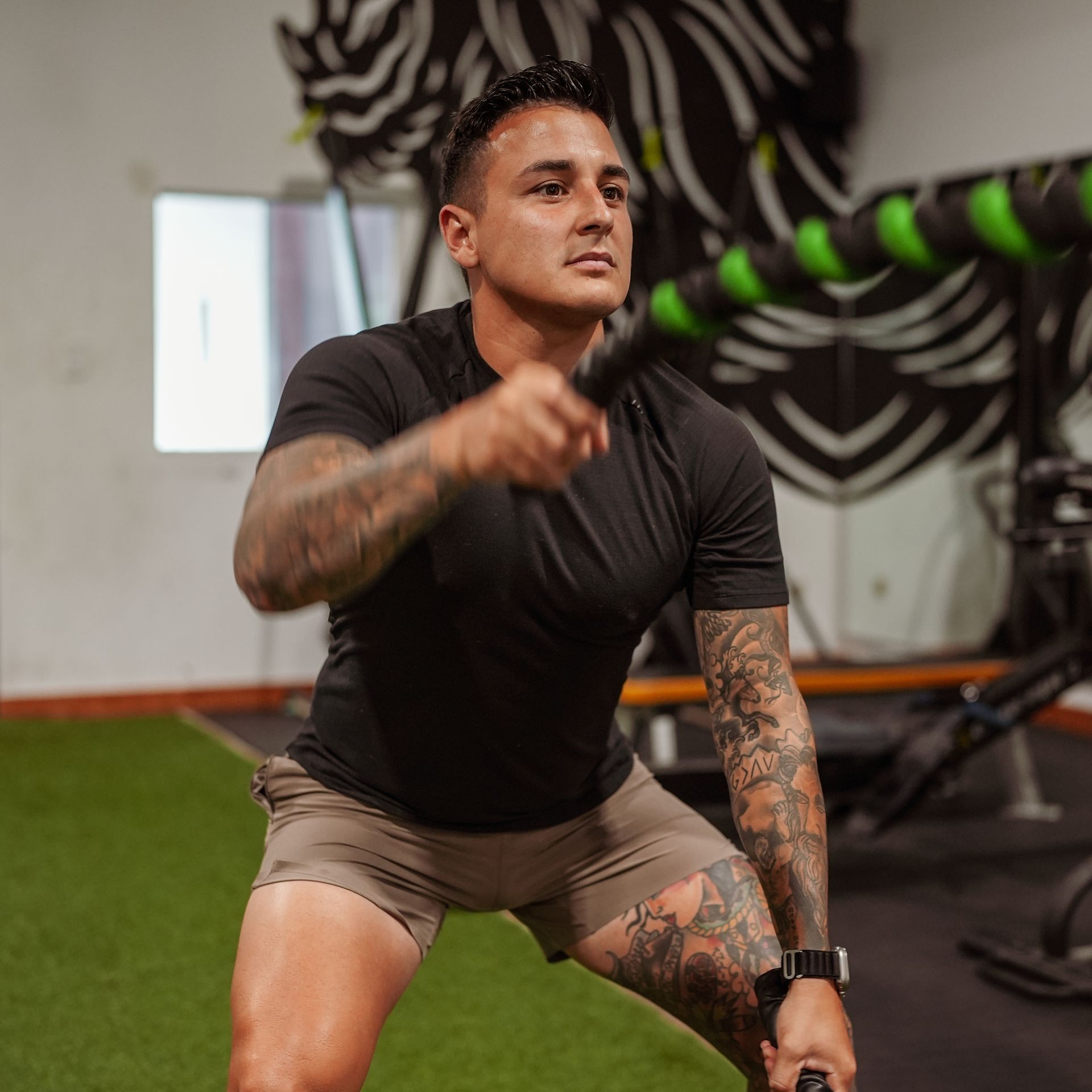 A man is squatting with a rope in a gym. FJ Fitness Personalized meal plan and workouts