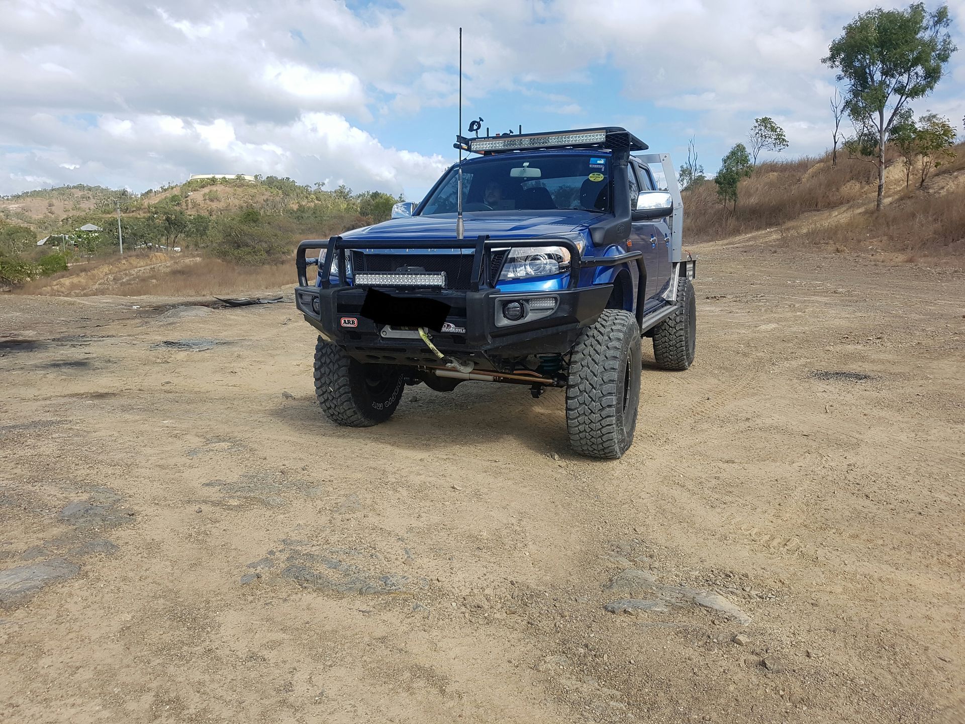 A Blue Off-Road Truck with A Winch and Light Bar Parked on A Dusty — Ironhide Customs In Garbutt, QLD