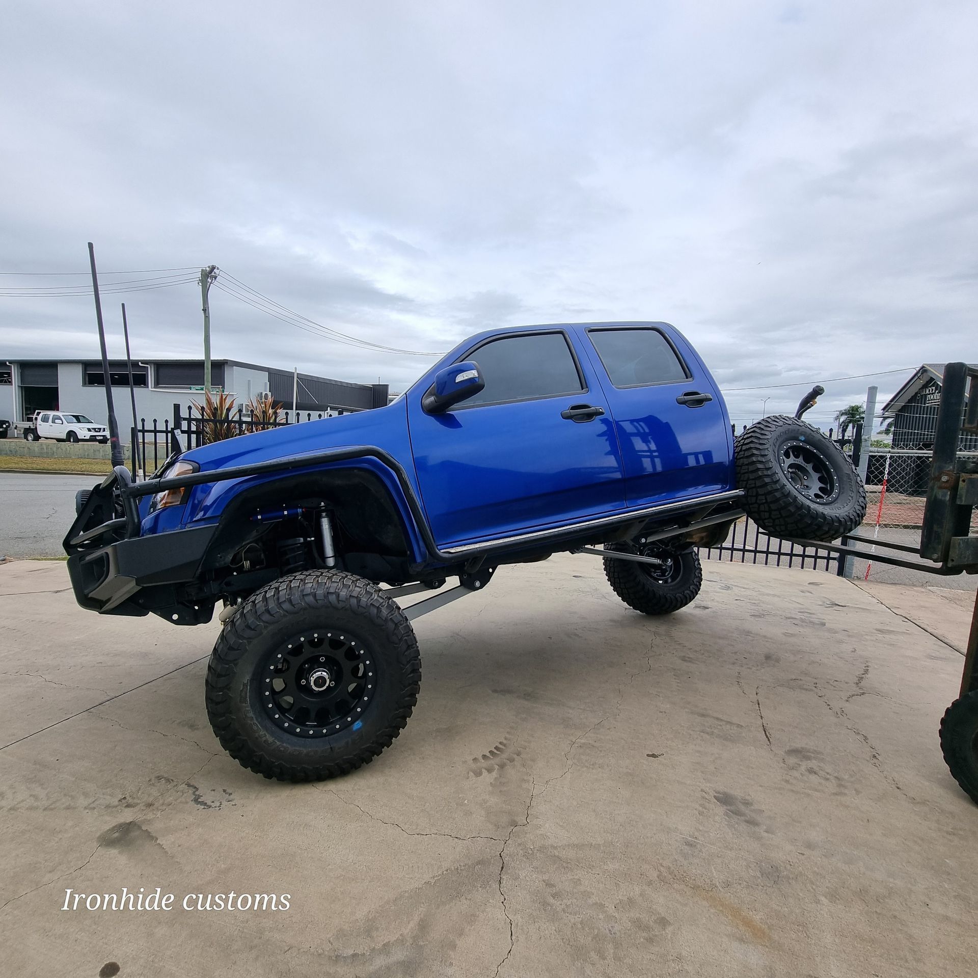 A Bright Blue, Highly Lifted Pickup Truck Suspended in The Air — Ironhide Customs In Garbutt, QLD