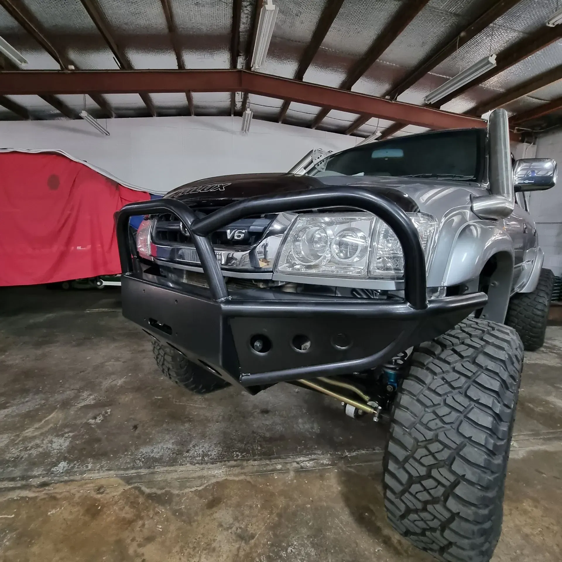 A Silver Lifted Pickup Truck with A Black Bull Bar and Snorkel Parked Inside a Garage — Ironhide Customs In Garbutt, QLD