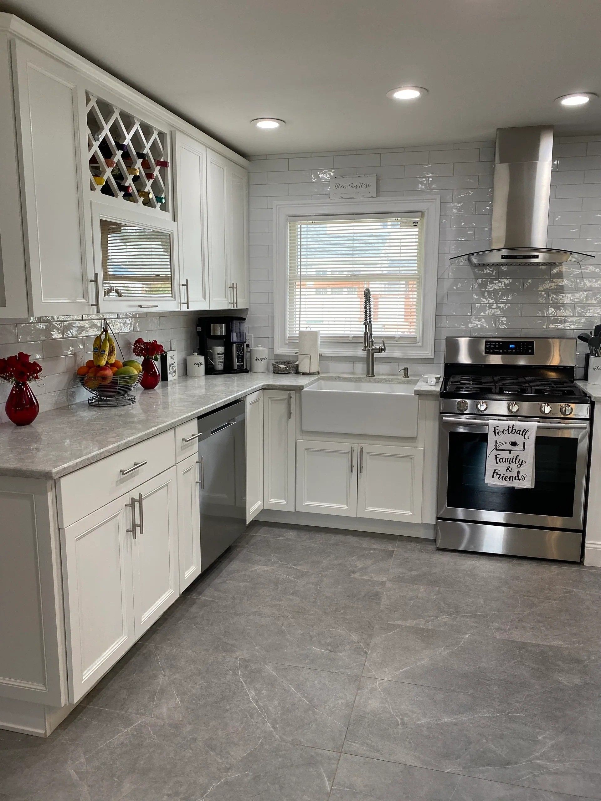 White kitchen with stainless steel appliances, gray countertop, and gray floor.