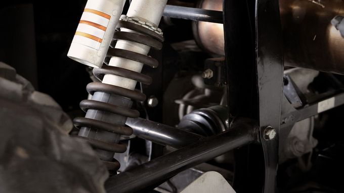 Close-up of a motorcycle rear suspension spring and shock absorber in a dark mechanical frame