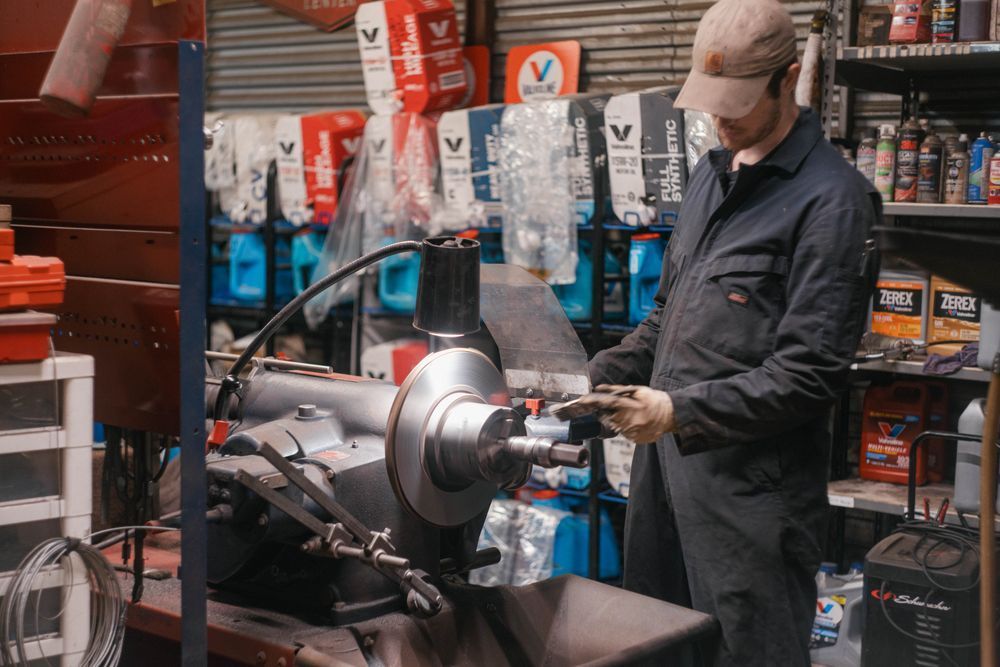 Person in a workshop using a lathe, surrounded by tools and packaged parts.