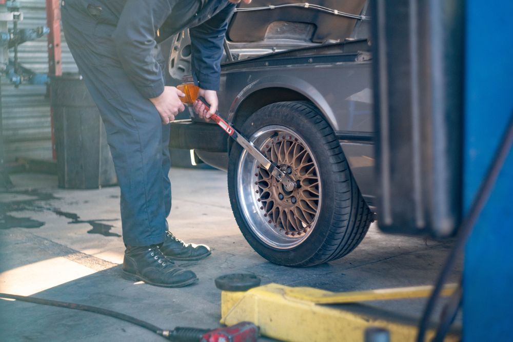 Mechanic using an air hose to inflate a car tire in a garage