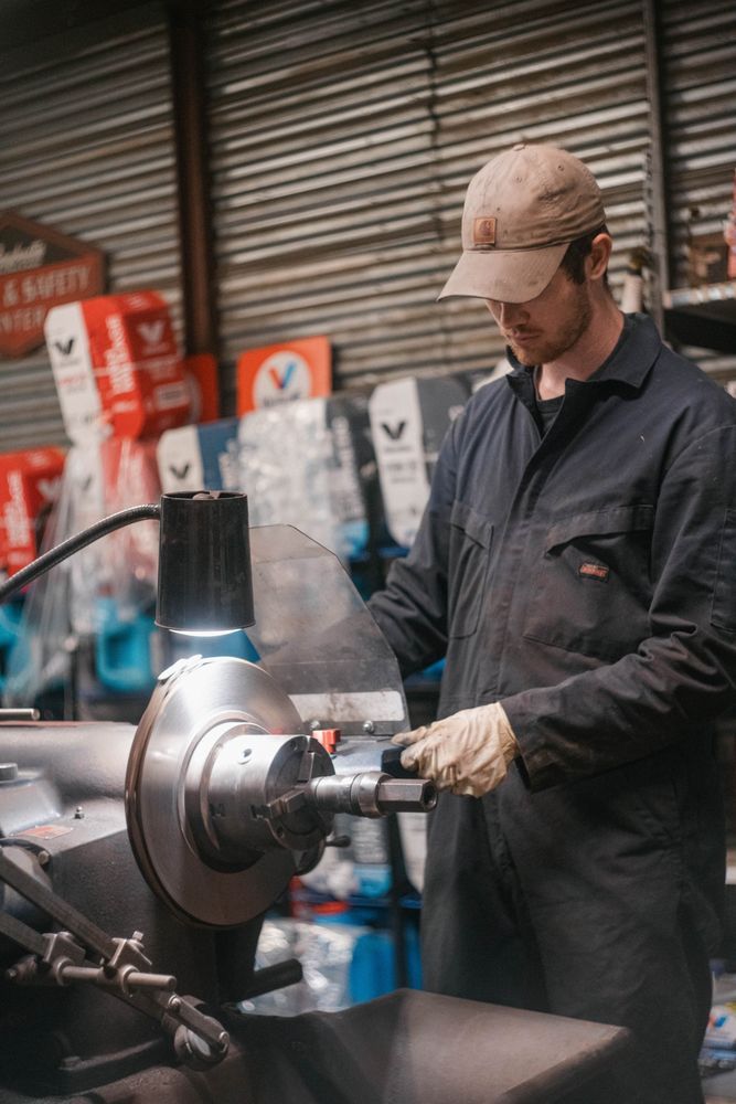 Mechanic in gloves working on a metal part with a grinder in a workshop