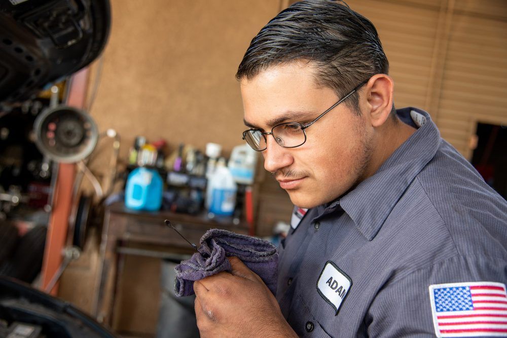 Mechanic cleaning a tool in a workshop, wearing glasses and a shirt with an American flag patch