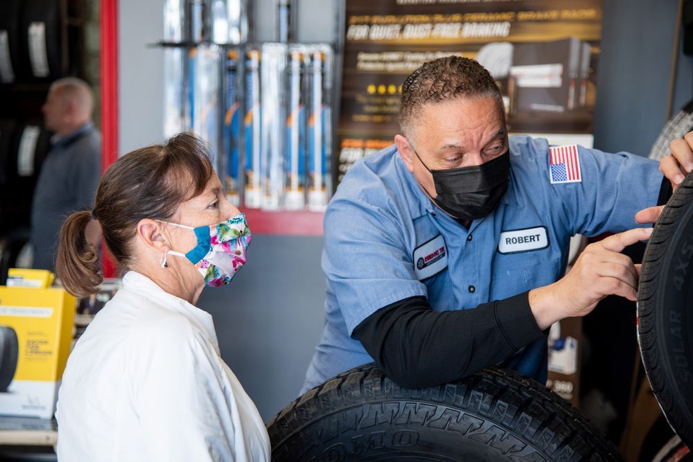 Mechanic showing a tire to a masked customer in an auto shop