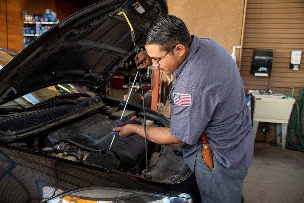 Mechanic inspecting a car engine with the hood open in a garage